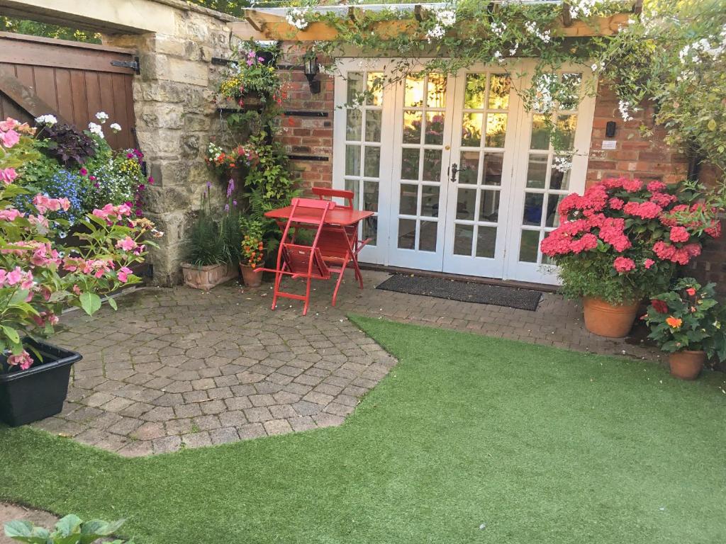 a patio with a table and chairs and flowers at Beech View in Malton