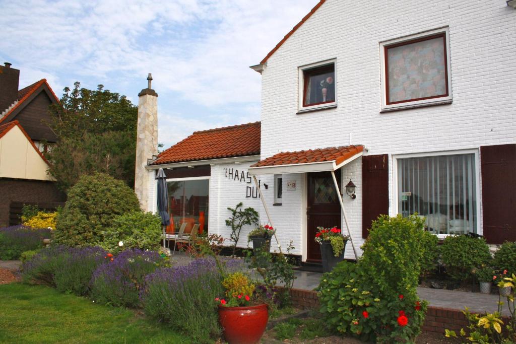 a white house with flowers in the yard at Villa 't Haasduin in Wijk aan Zee