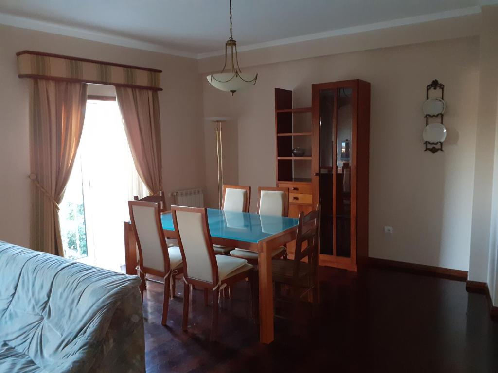 a dining room with a table and chairs and a bed at Casa da Praça in Sertã