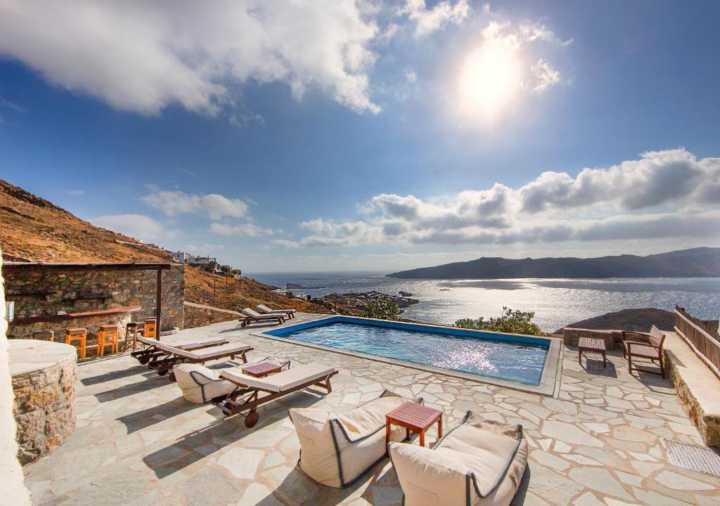 a swimming pool with chairs and a view of the water at Villas Kappas in Agios Sostis Mykonos