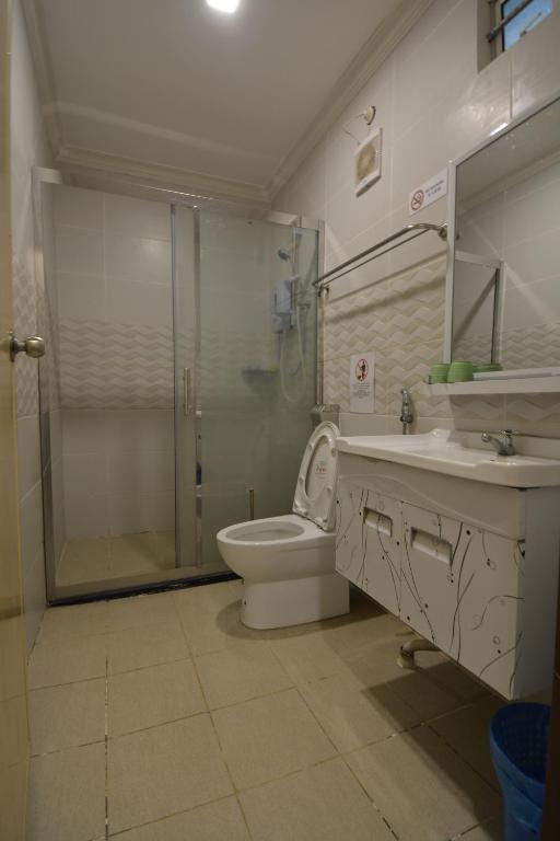 a bathroom with a shower and a toilet and a sink at Hemingway Cottage 海明威度假屋 in Semporna