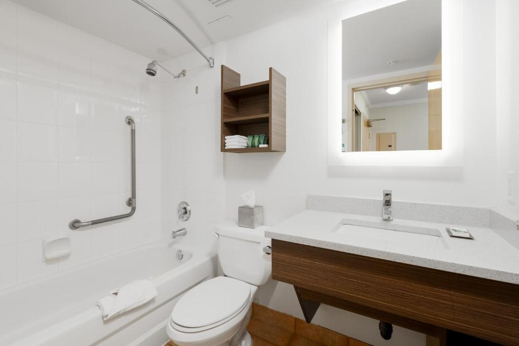 a white bathroom with a toilet and a sink at GEC Granville Suites Downtown in Vancouver
