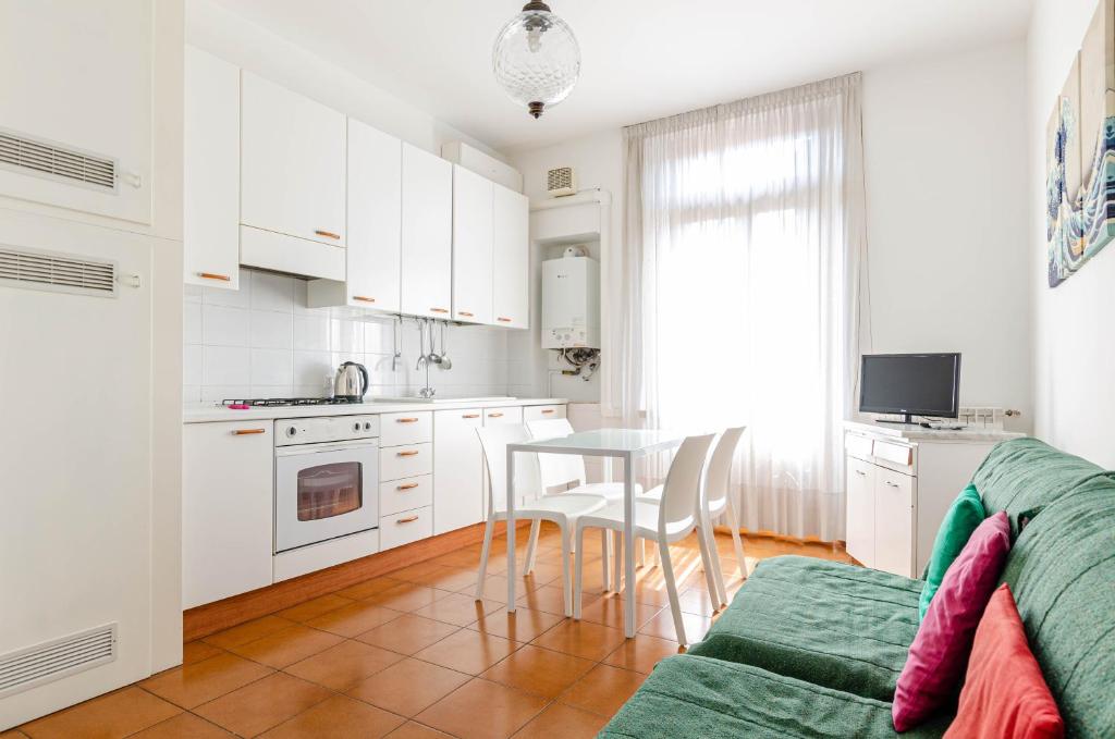 una cucina con armadi bianchi, tavolo e sedie di Easy Central Apartment - Milano Porta Romana a Milano