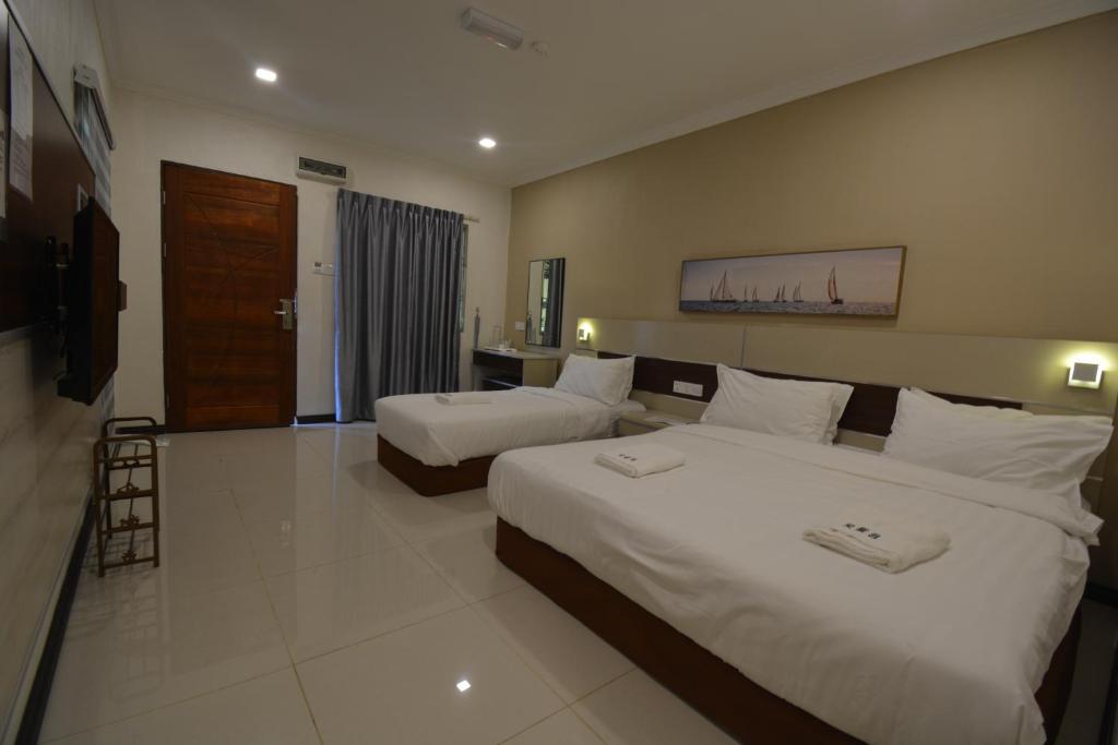 a hotel room with two beds and a television at Hemingway Cottage 海明威度假屋 in Semporna