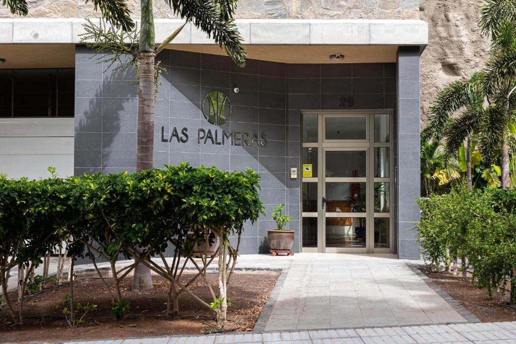 プエルト・デ・モガンにあるApartamentos Las Palmerasの椰子を読む看板のある建物