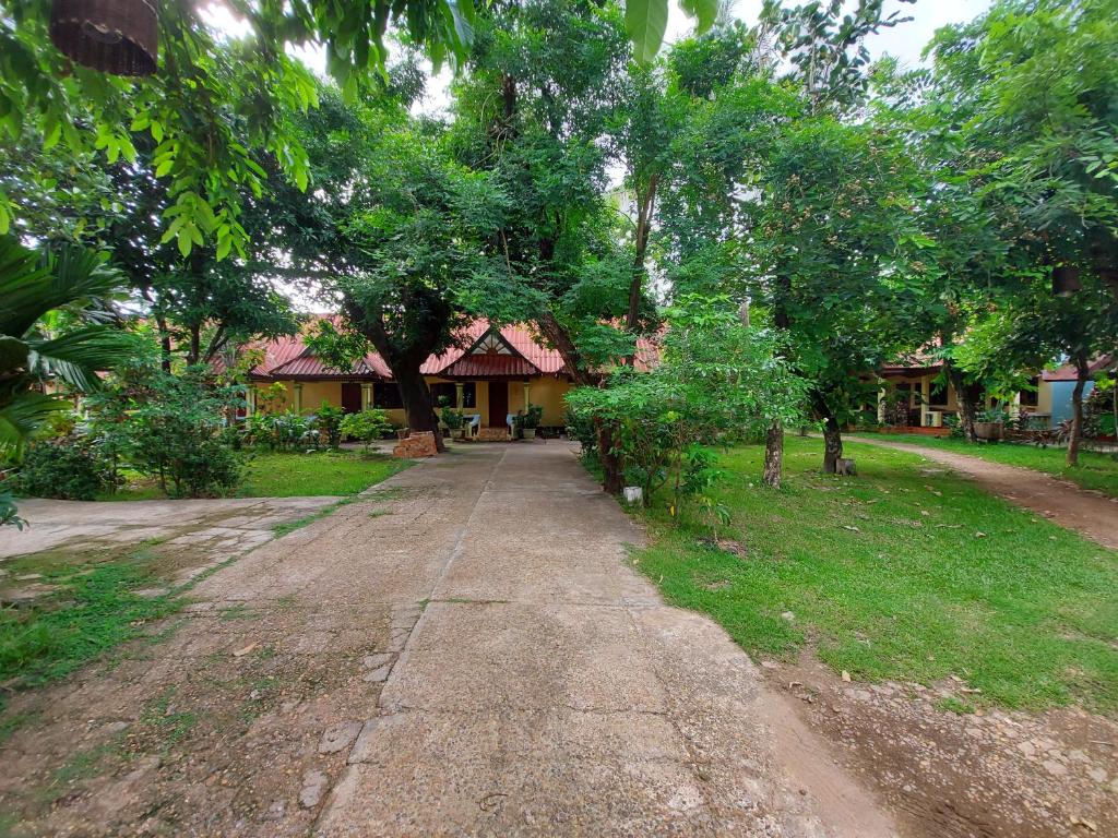 uma estrada de terra em frente a uma casa com árvores em Anouxa Riverview Guesthouse em Champasak