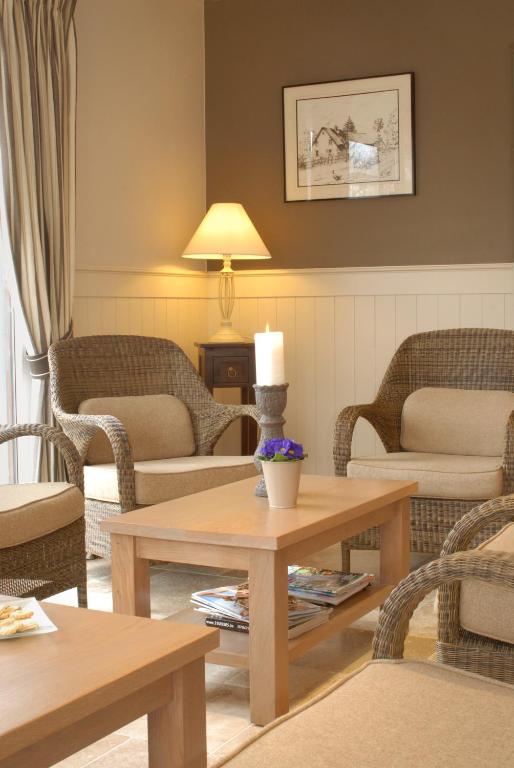 a living room with couches and tables and a lamp at Hotel Eifelland in Butgenbach