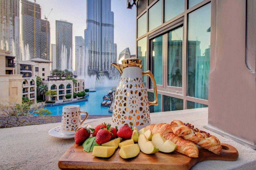 a table with a tray of fruit and a tea kettle at Durrani Homes - Souk Al Bahar Luxury Living with Burj & Fountain Views in Dubai