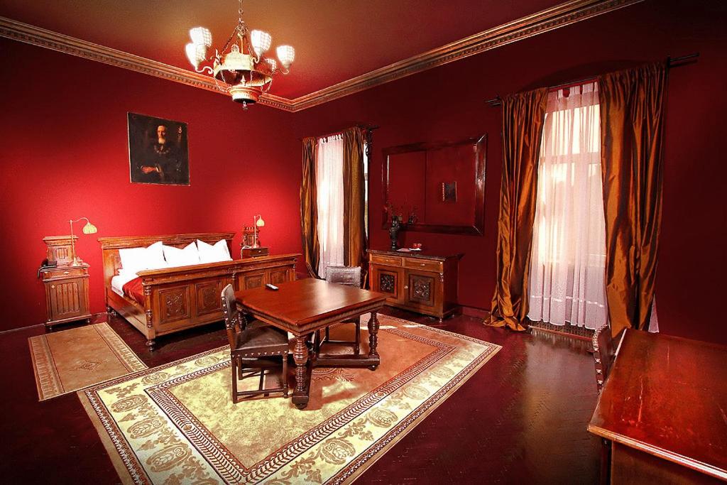 una camera rossa con un letto e un tavolo di Hotel Poesis Satu Mare a Satu Mare