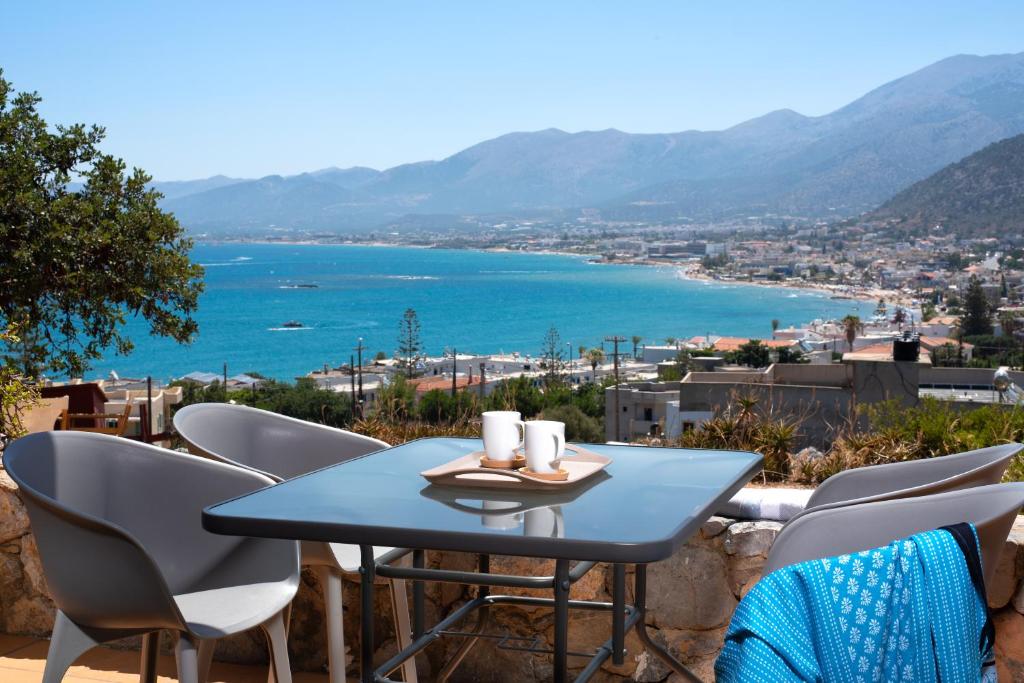 een tafel en stoelen op een balkon met uitzicht op het water bij Escape In Blue in Stalida