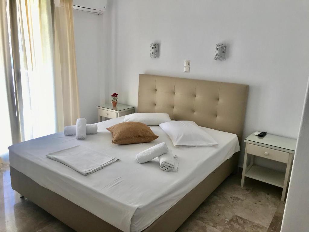 un letto con lenzuola bianche e asciugamani di Vassiliki Rooms a Paroikia