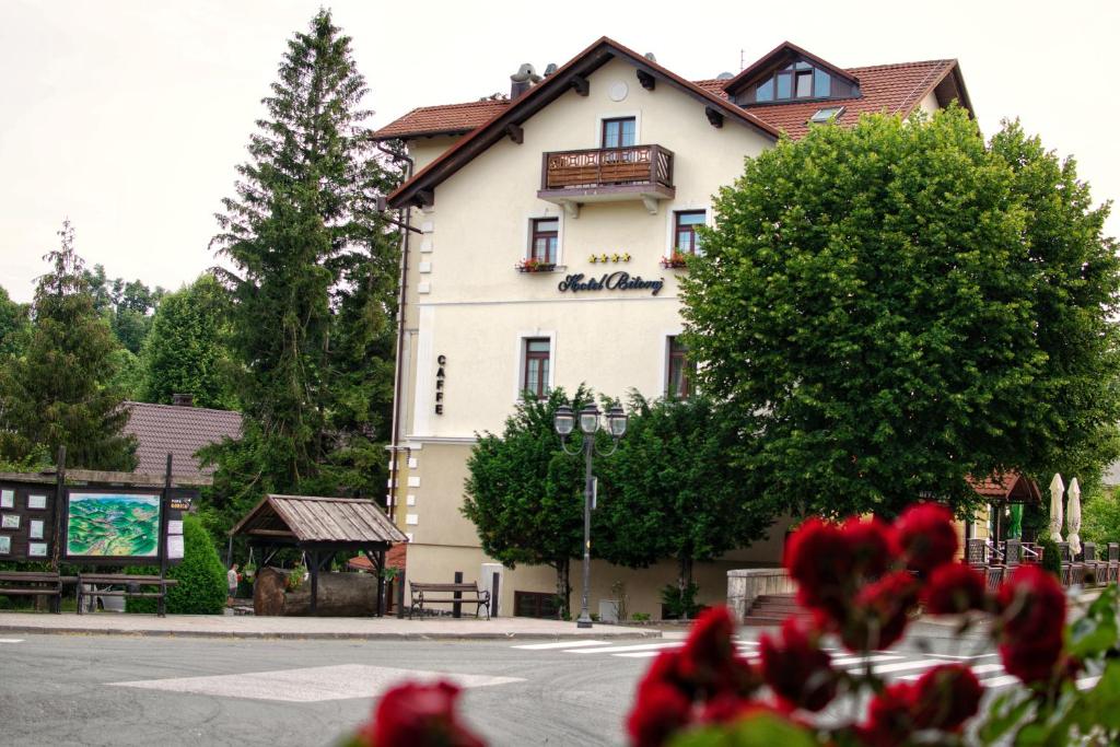 ein großes weißes Gebäude an der Straßenseite in der Unterkunft Hotel Bitoraj Fužine in Fužine