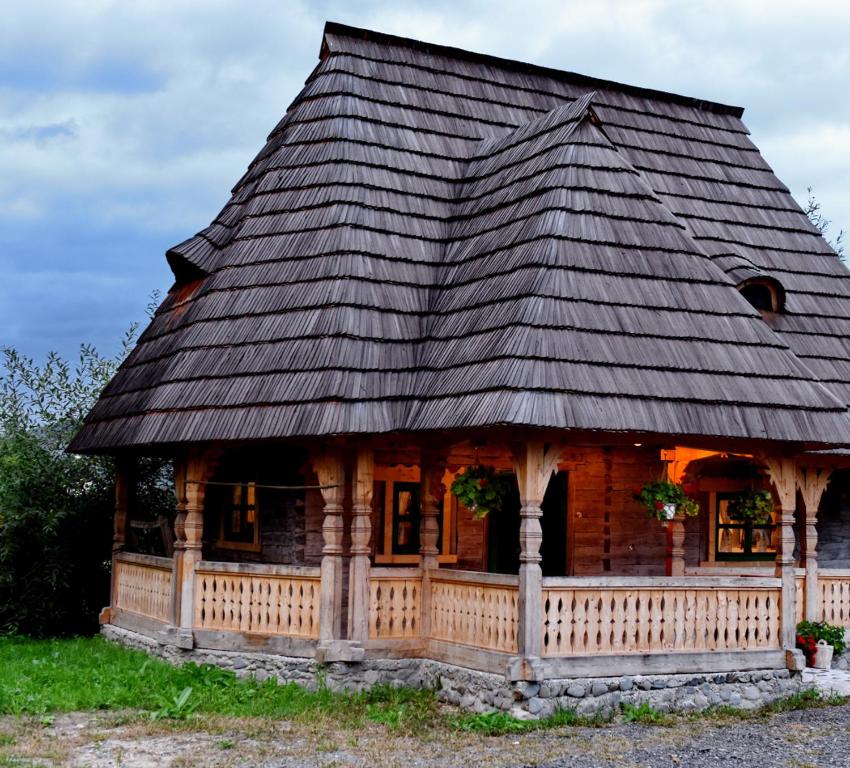 a log cabin with a black roof at Căsuța Maramureșeană din Vadu Izei in Vadu Izei