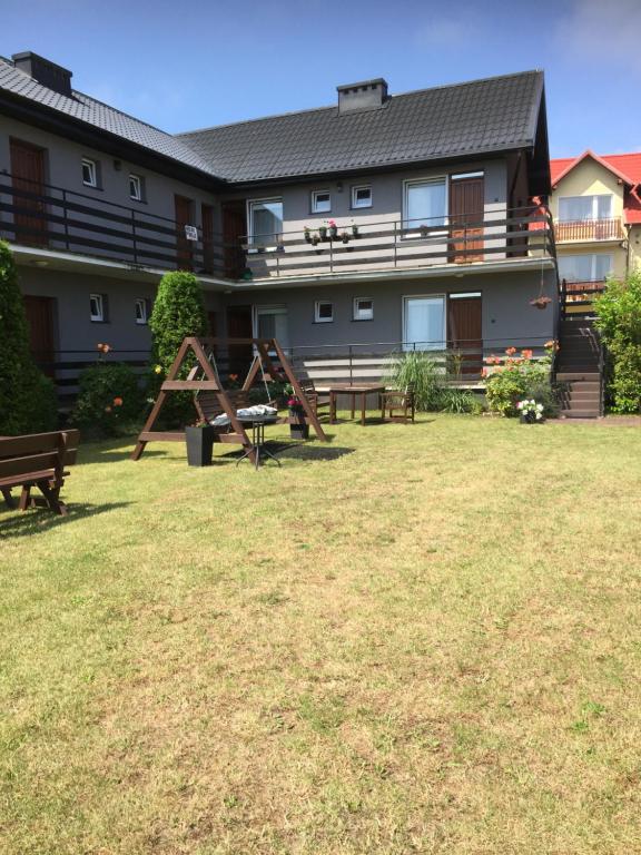 un gran edificio con un parque infantil en el patio en Pensjonat ''TRYTON'', en Karwia