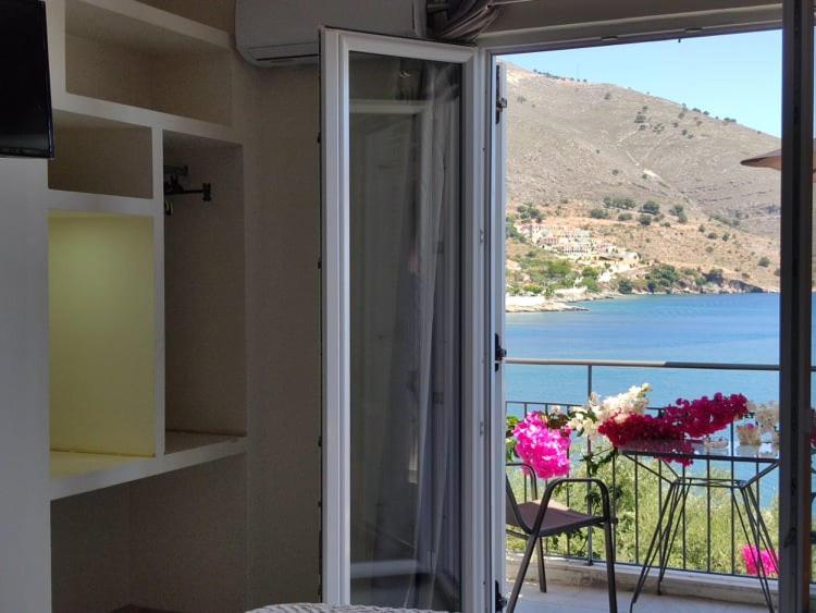 a room with a balcony with a view of the water at Ballas Apartments in Ayia Evfimia