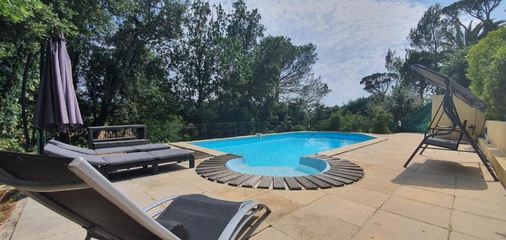 - une piscine avec une chaise et un parasol dans l'établissement Saint Raphael - Appartement dans villa au calme à Valescure y- Prix inchangés, à Saint-Raphaël