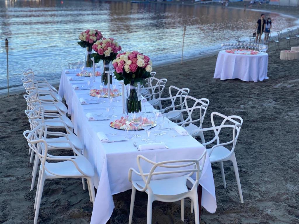 a long table with white chairs and flowers on a beach at Hotel Miramare & Spa in Sestri Levante