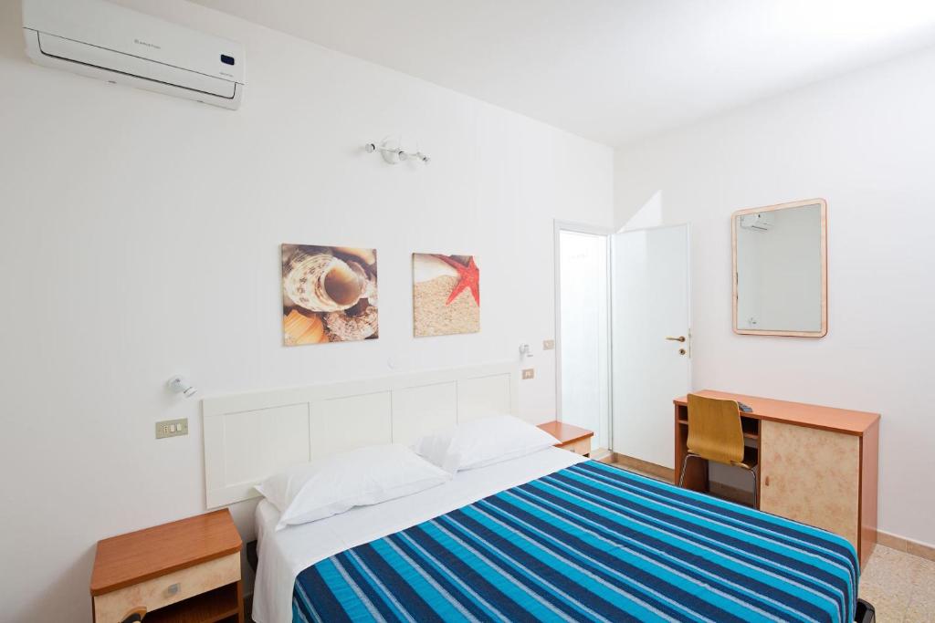 Habitación blanca con cama y escritorio en Hotel Helios, en Riccione