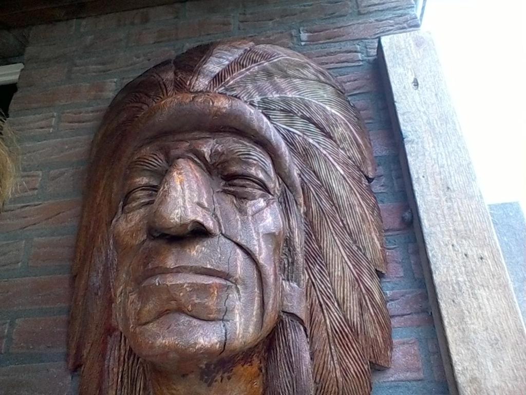 a statue of an old woman on a brick wall at De indiaan in Noord-Scharwoude