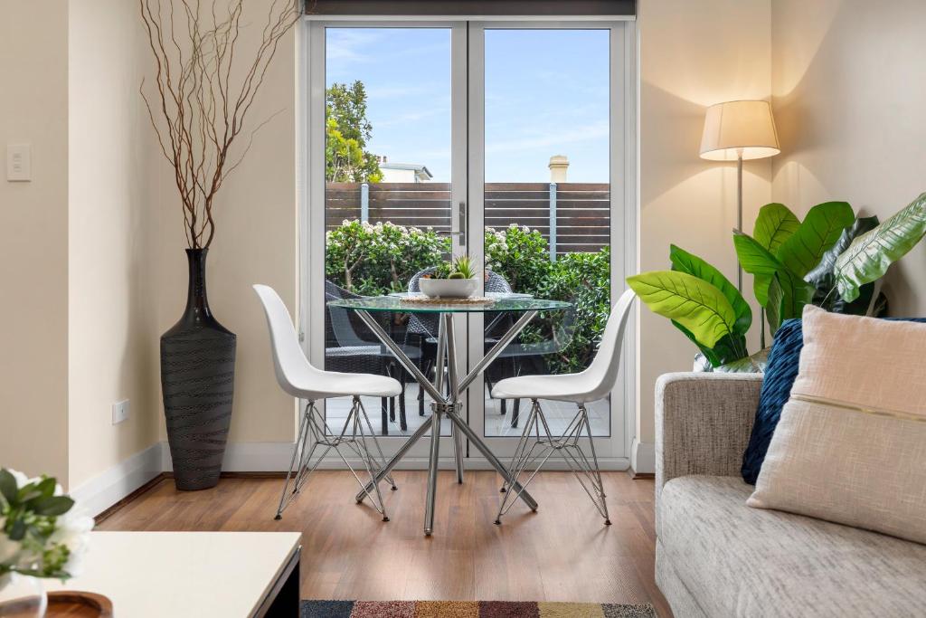 een woonkamer met een glazen tafel en witte stoelen bij The Banq Apartments by Urban Rest in Sydney