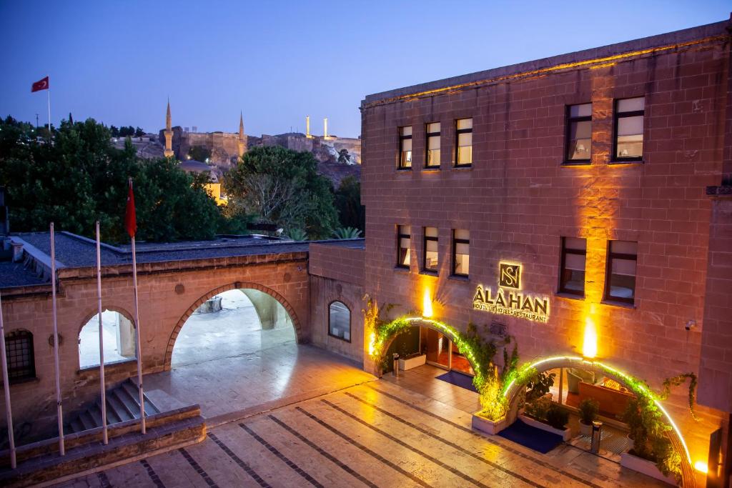 a large brick building with an archway next to a bridge at ÂLÂ HAN BOUTIQUE HOTEL in Urfa