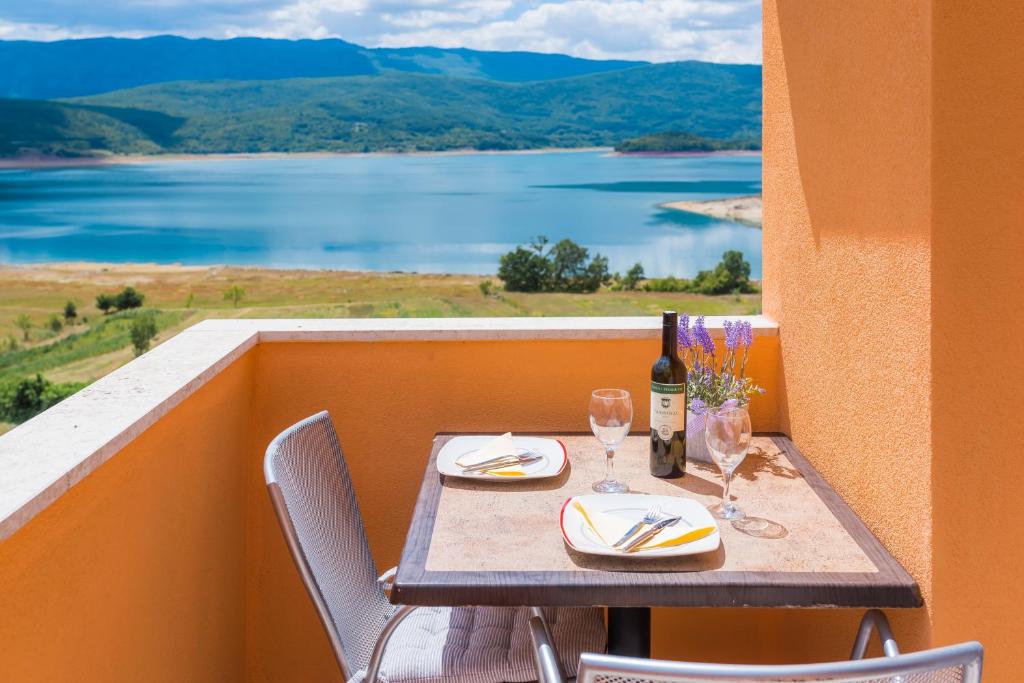 a table with a bottle of wine and glasses on a balcony at Rooms and Apartments Budiša in Vrlika