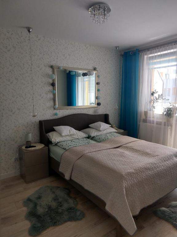 - une chambre avec un grand lit et un miroir dans l'établissement Apartament FALA-Miodowy Dom, à Kołobrzeg