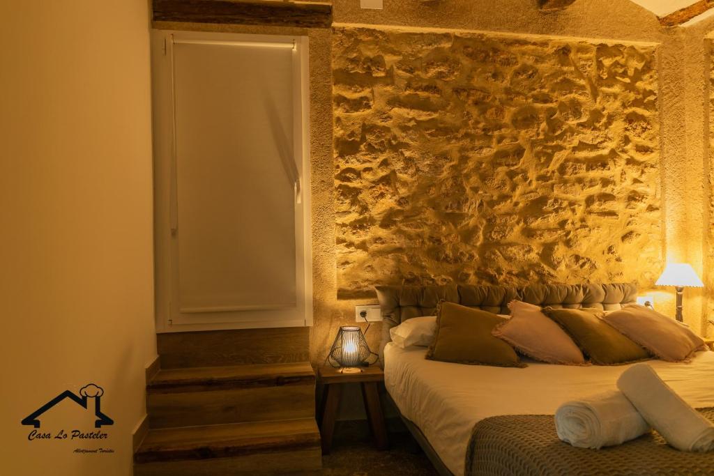 1 dormitorio con cama y pared de piedra en CASA LO PASTELER en Roquetas