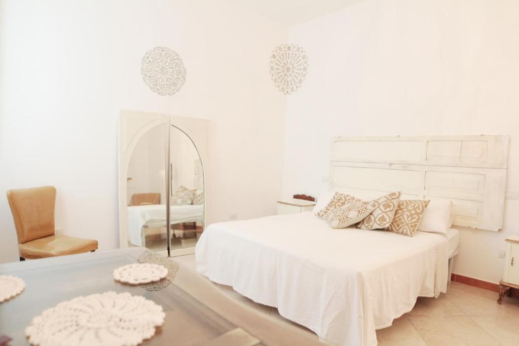 Habitación blanca con cama y espejo en Terra Oltre B&B, en Trepuzzi