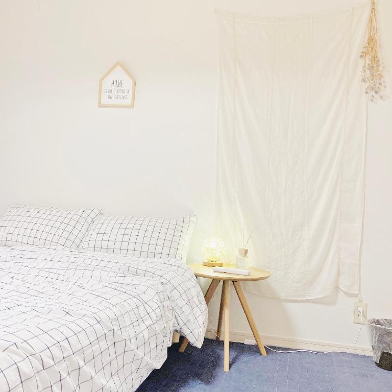 1 dormitorio con cama y mesa junto a una ventana en 林林の民宿-NISHIKUJIO 別館, en Osaka