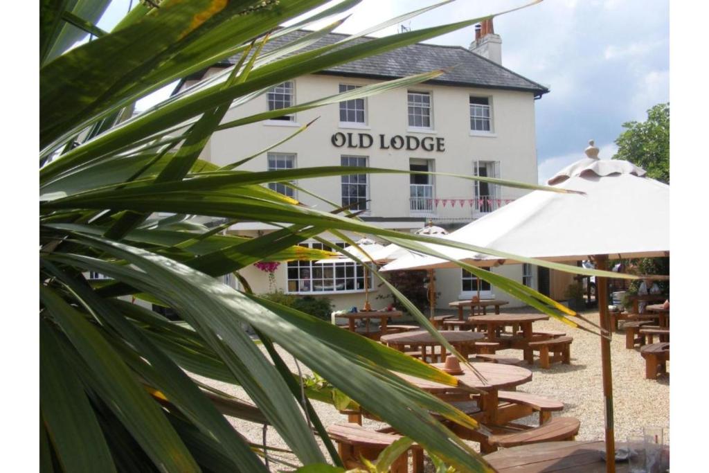 an old lodge building with tables and umbrellas at The Old Lodge in Gosport