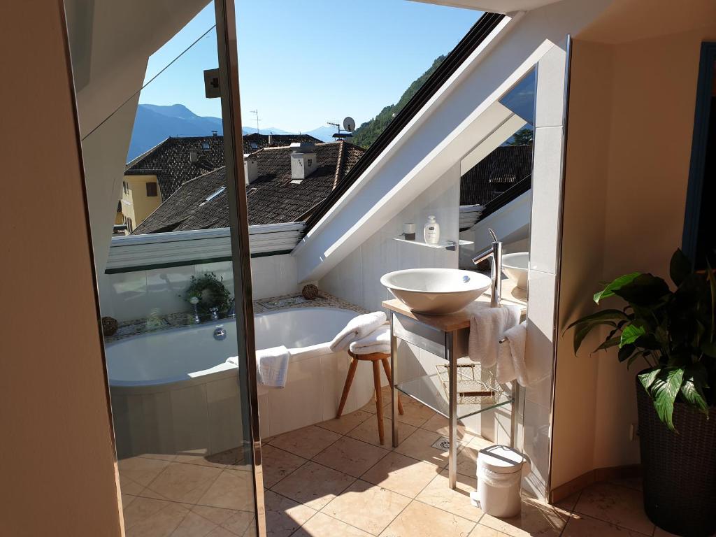 een badkamer met een bad en een wastafel op een balkon bij viaDolceVita - Blaue Gästewohnung in Lana