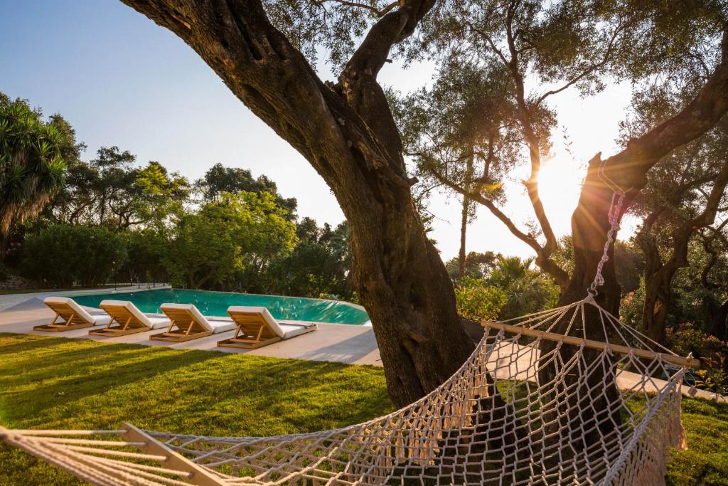 una hamaca bajo un árbol junto a una piscina en Ionian Garden Villas - Villa Olea en Benitses