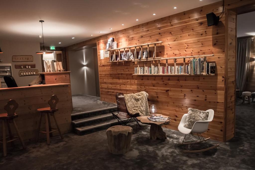 レ・デュー・アルプにあるオテル レ フロコンの木製の壁の客室で、椅子2脚とテーブル1台が備わります。