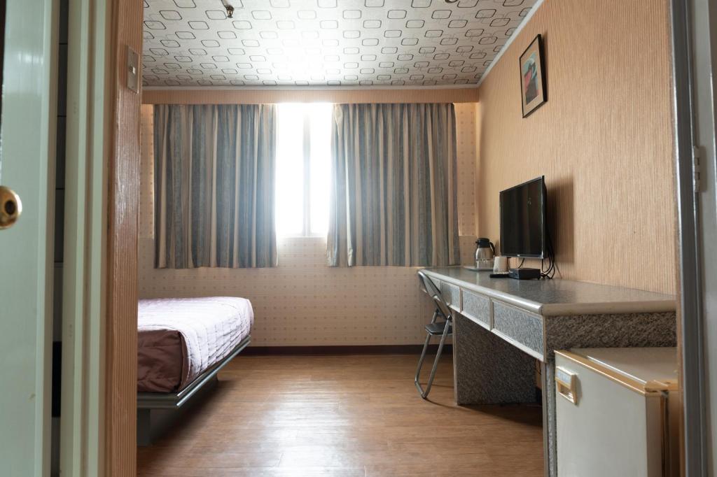 a hotel room with a bed and a desk with a television at Tong Hsin Hotel in Pingtung City