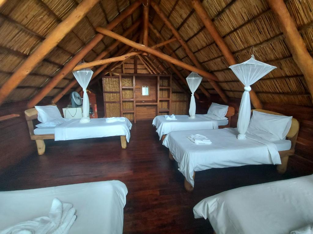 Habitación con 4 camas en una habitación con techo de paja en East Africa Safaris en Chizavane