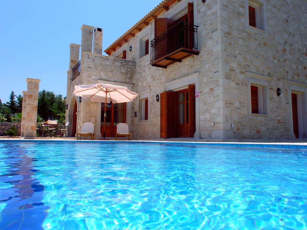 a swimming pool in front of a house with an umbrella at Cretan Exclusive Villas in Agia Triada