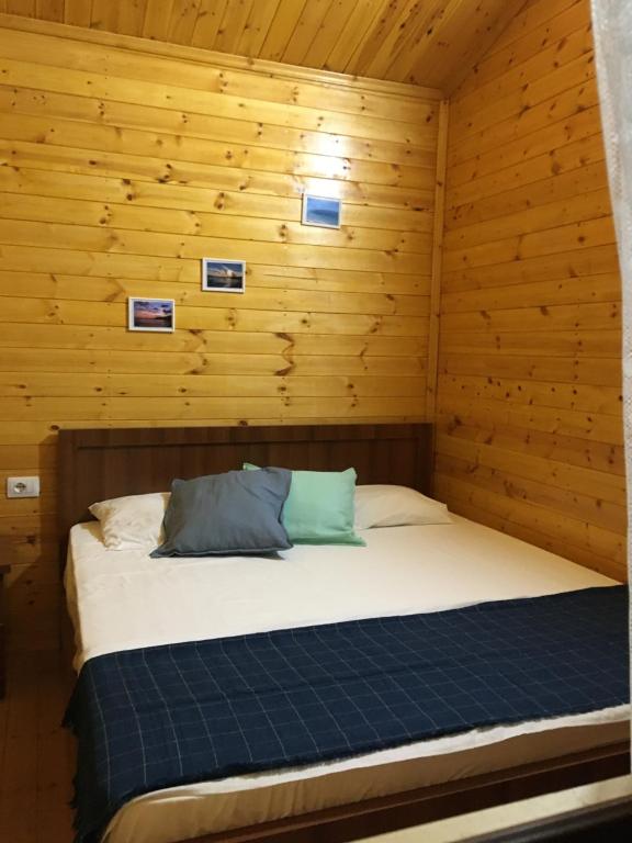 a bed in a cabin with wooden walls at Violet Village in Borsh