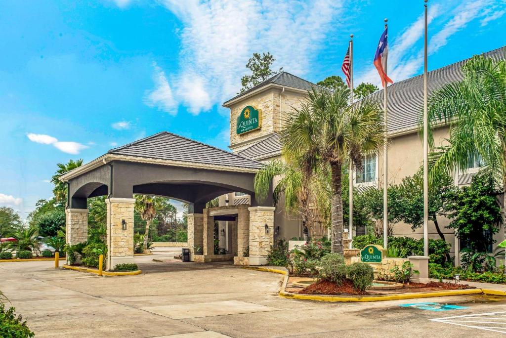un hotel con un edificio con palmeras delante en La Quinta Inn & Suite Kingwood Houston IAH Airport 53200, en Kingwood