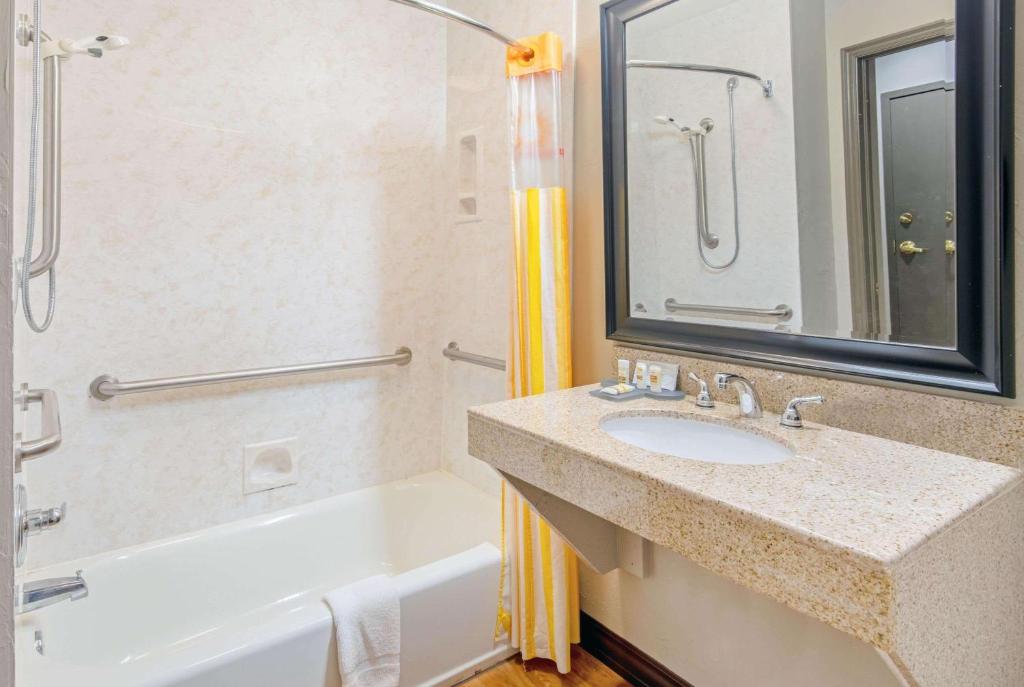 a bathroom with a sink and a tub and a mirror at La Quinta by Wyndham Oklahoma City - Moore in Moore