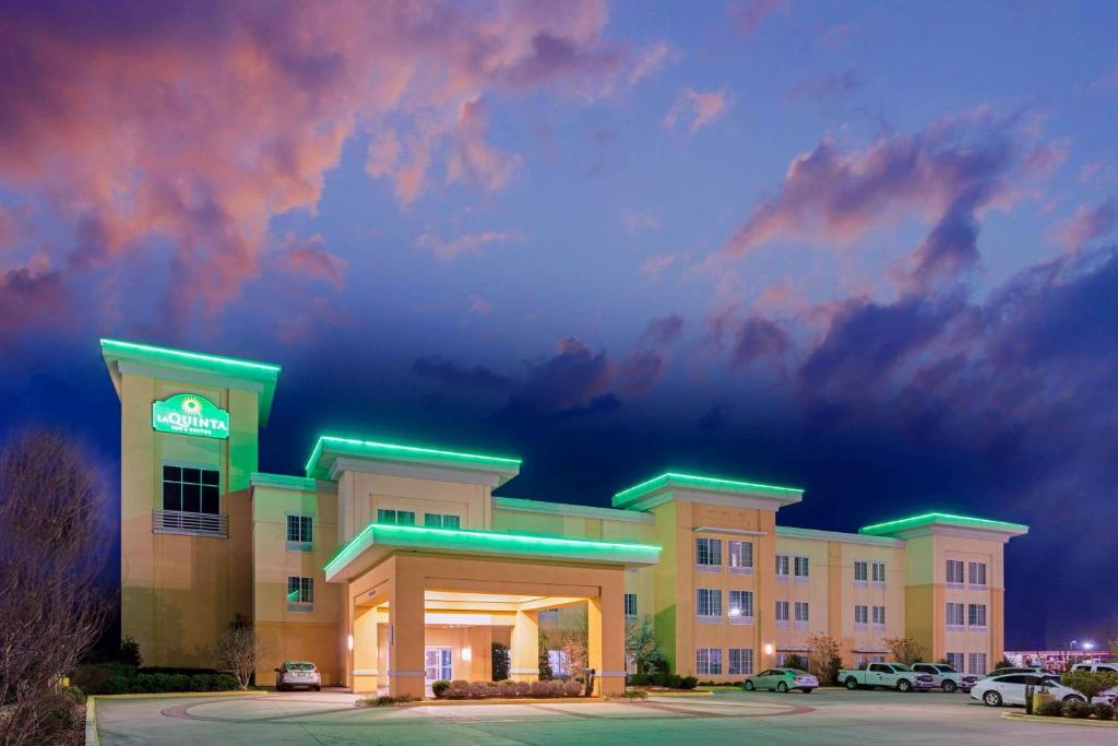 a hotel with cars parked in a parking lot at La Quinta by Wyndham Muskogee in Muskogee