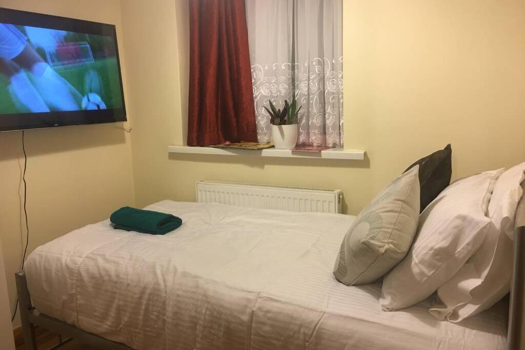 a bedroom with a bed with a flat screen tv at F3 Cosy Single Room (Sandycroft Guest House) in London