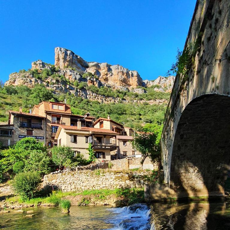 a bridge over a river with houses and a mountain at Casa Rural Rudron in Valdelateja