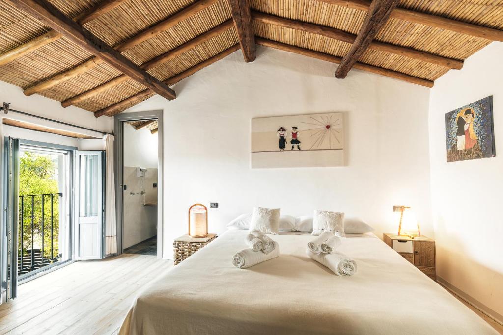 una camera con un grande letto in una stanza con soffitti in legno di Sa Crai B&B - Sardinian Experience a Lotzorai