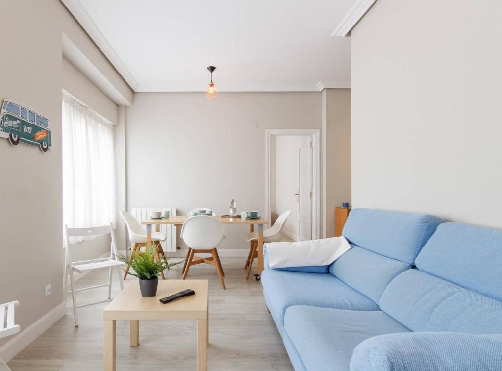 ein Wohnzimmer mit einem blauen Sofa und einem Tisch in der Unterkunft Prestancia Apartament II by the urban hosts in Bilbao