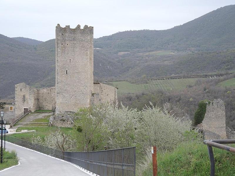 um velho castelo com uma cerca ao lado de uma estrada em CASA PIERA em Acciano