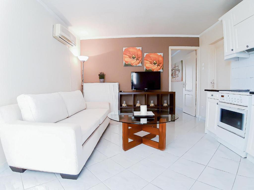 een woonkamer met een witte bank en een tafel bij Kalliopi's apartment in Athene