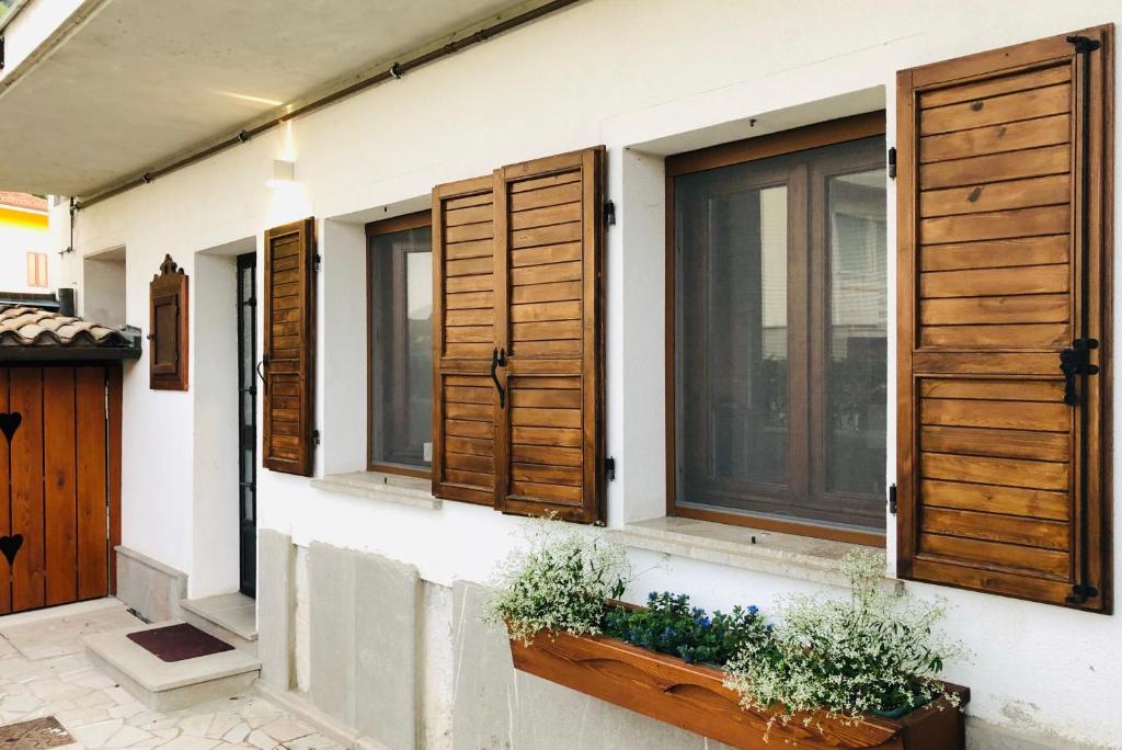 Pal Biel Affittacamere Avasinis في Avasinis: منزل به مصارع نوافذ خشبية ونباتات عليه