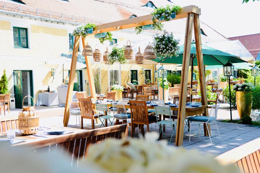 restauracja na świeżym powietrzu ze stołami, krzesłami i parasolem w obiekcie Forsthaus Wörnbrunn w mieście Grünwald