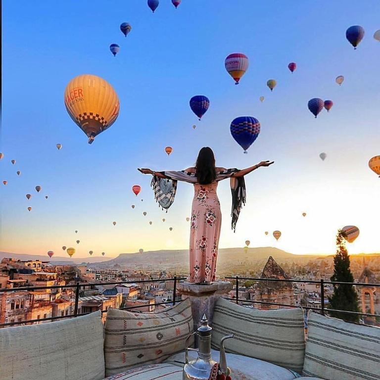 a woman standing on top of a tower with balloons at Sakli Cave House in Avanos
